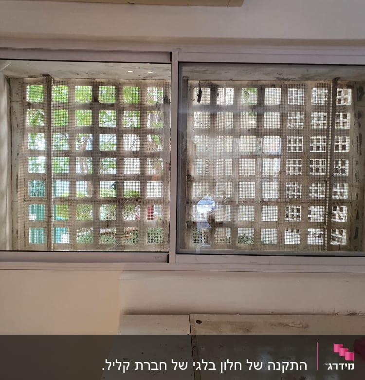 חלון אלומיניום עם מסגרת לבנה וקיר רשת מאחוריו